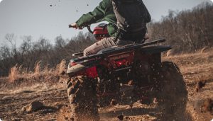Man riding 4-wheeler through mud